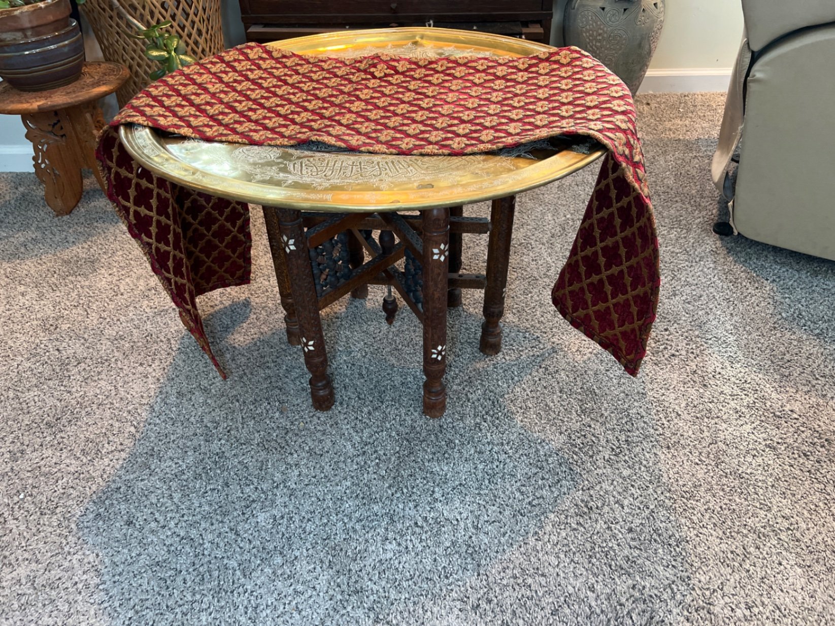 Round brass engraved tray/table with carved wooden chair frame, and red patterned rug - image 10 of 11