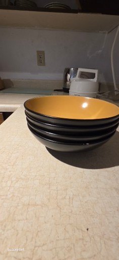 Stack of yellow-inside, black-outside bowls with kitchenware and tea box - image 1 of 8