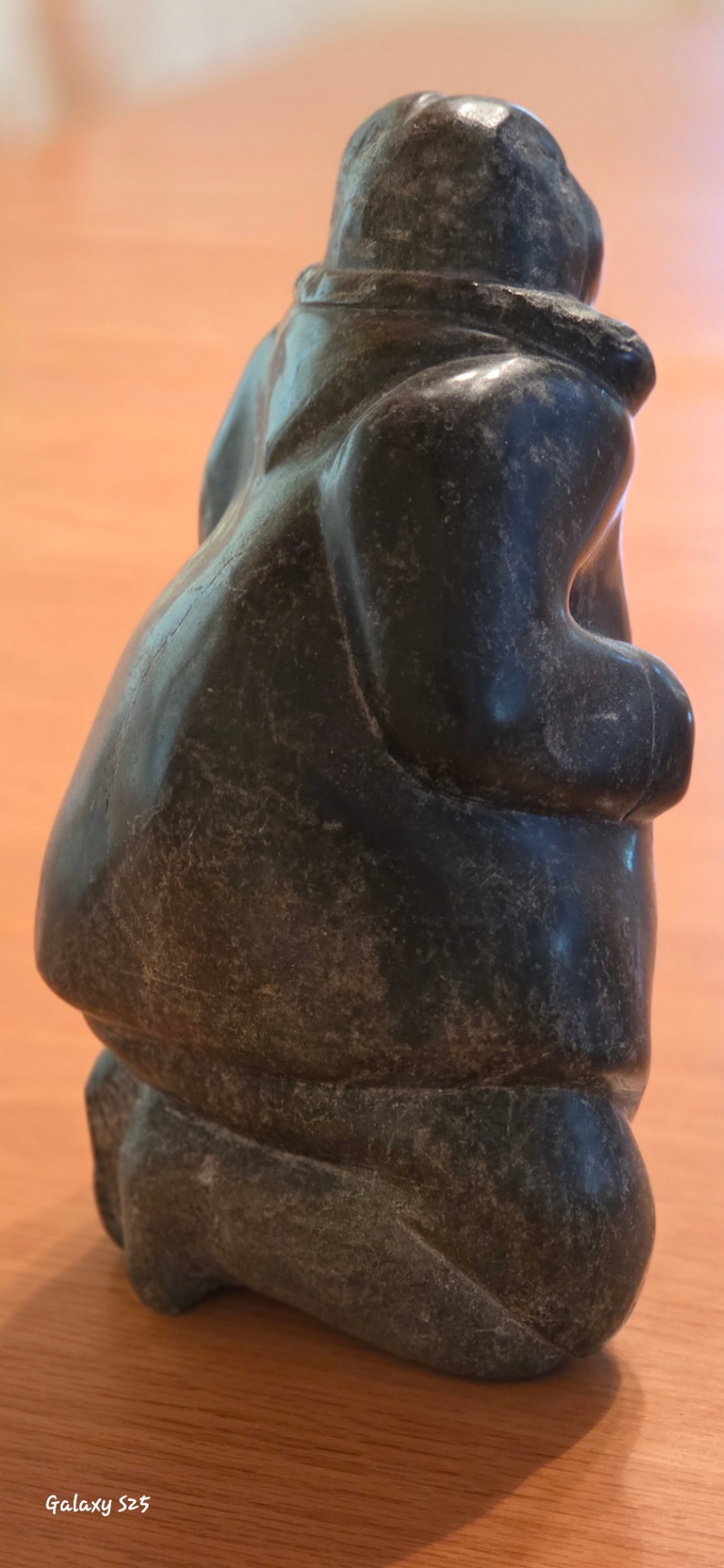Inuit Soapstone Carving – Kneeling Figure in Traditional Parka Hand-carved stone sculpture depicting a kneeling Inuit figure wearing a traditional hooded parka, with detailed facial features and a naturalistic, weighted posture. - image 2 of 3