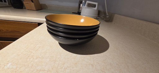 Stack of yellow-inside, black-outside bowls with kitchenware and tea box - image 3 of 8