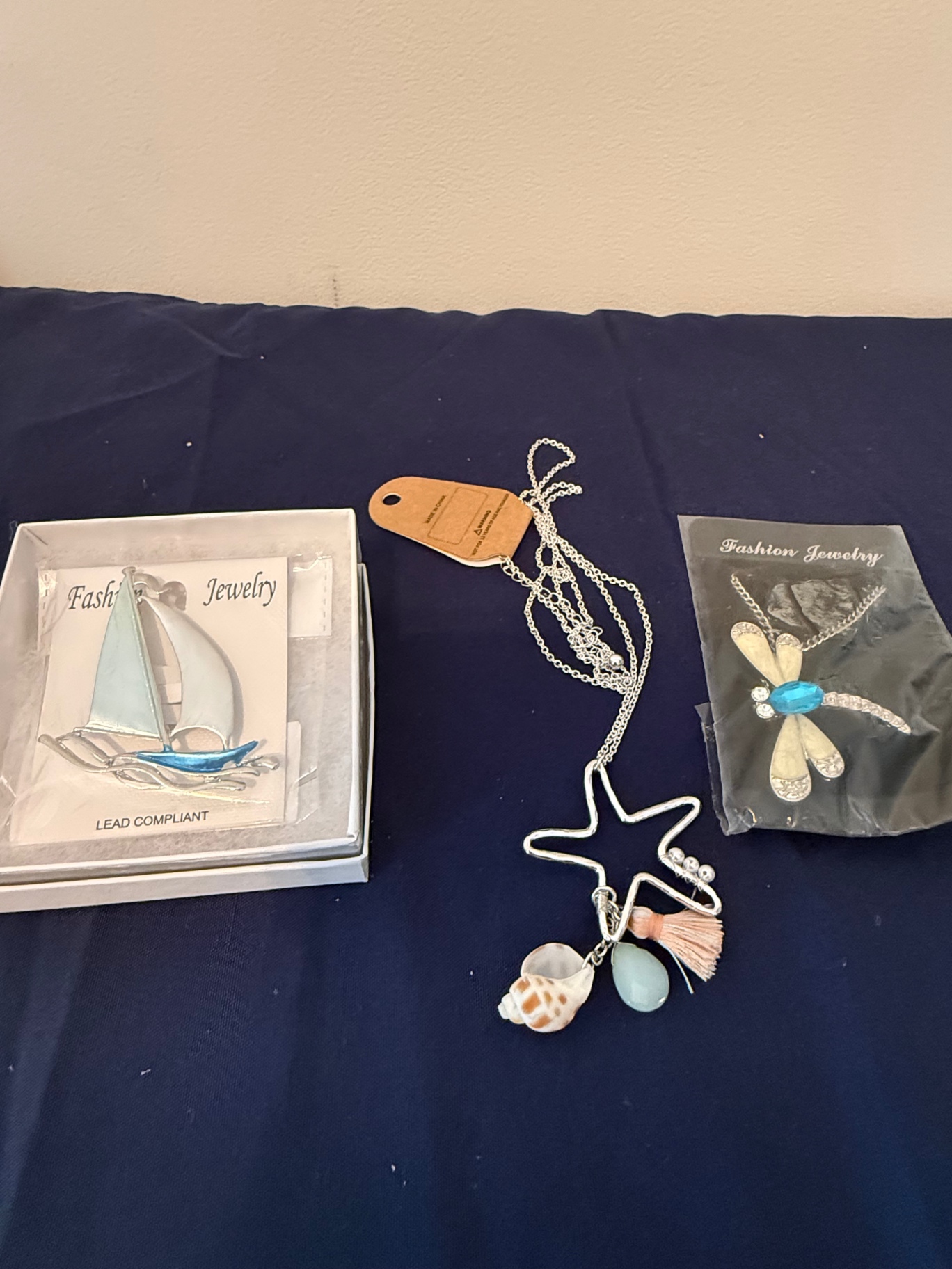 Assorted fashion jewelry: sailboat pendant, dragonfly brooch, and shell charms - image 1 of 4