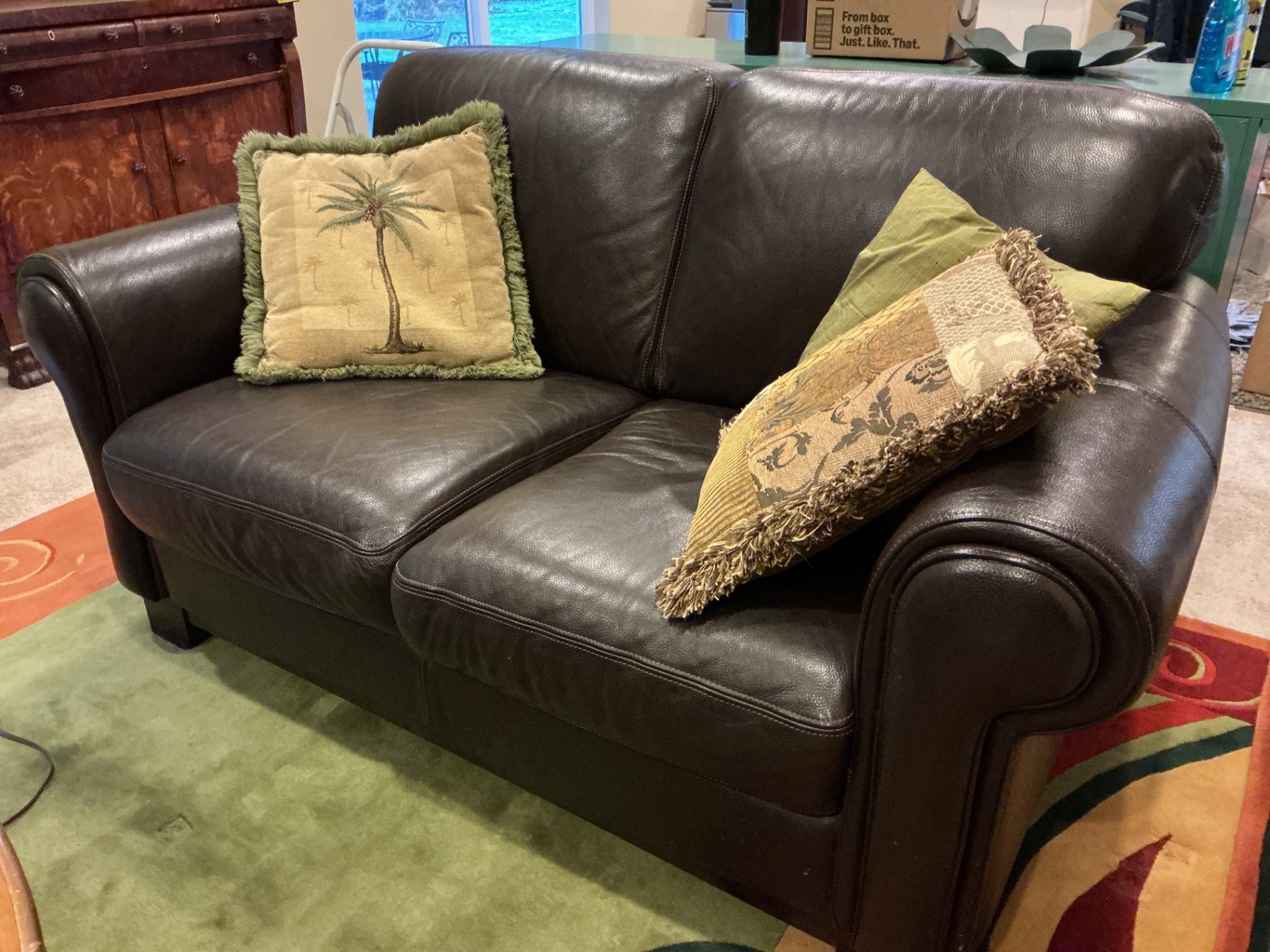 Dark brown leather loveseat with decorative pillows - image 1 of 10