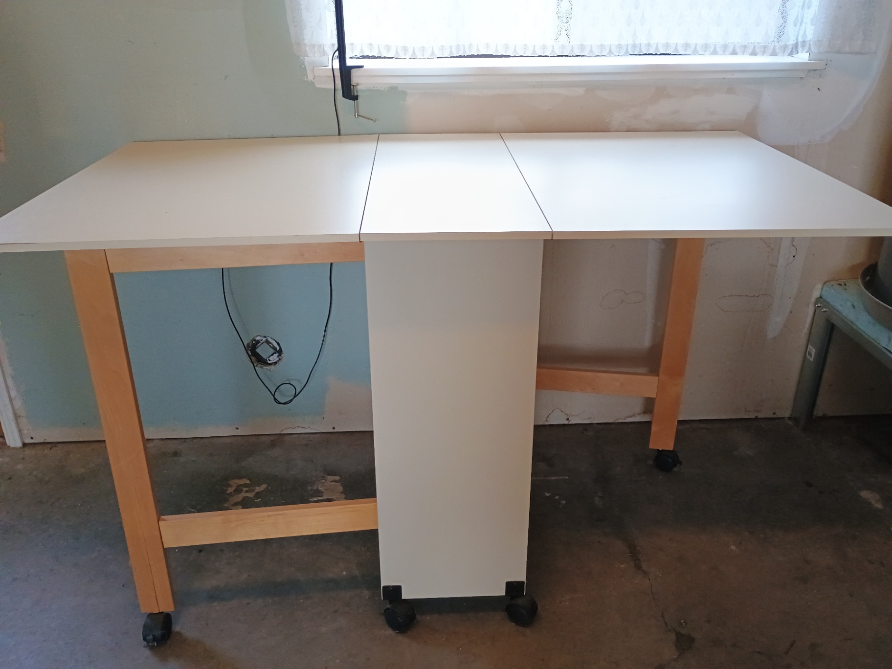 White foldable table with central pedestal and wooden legs on casters - image 1 of 6