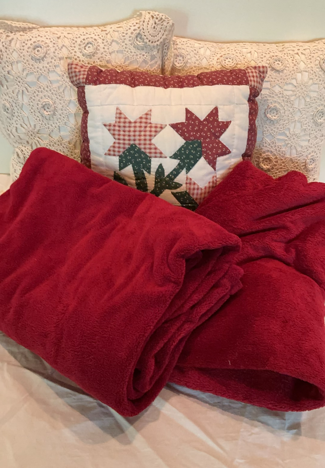 Decorative pillows with crocheted lace covers and red throw blanket - image 1 of 5