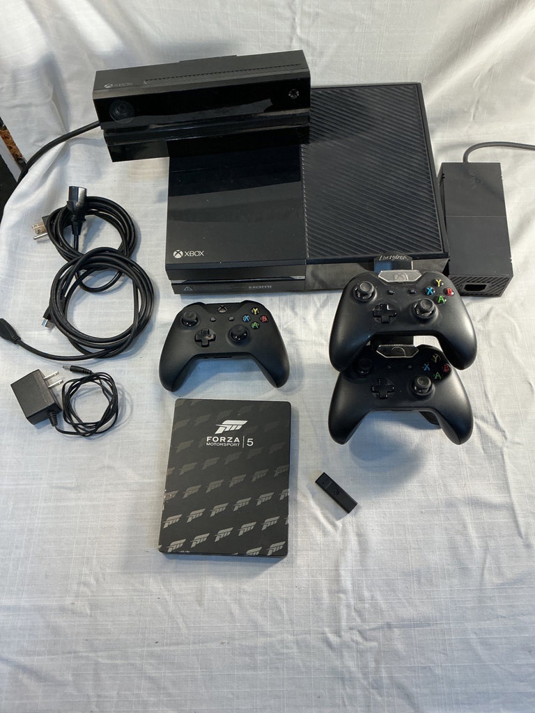 Xbox One X console with three controllers and a game - image 1 of 8