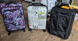 Three rolling suitcases: purple floral, cityscape white, and black - thumbnail 2 of 5