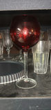 Assorted glassware with burgundy wine glass, red candle, and orange ridged baking mold - thumbnail 5 of 8