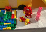 A yellow plastic school bus loaded with a bag of assorted colorful legos. - thumbnail 2 of 6