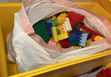 A yellow plastic school bus loaded with a bag of assorted colorful legos. - thumbnail 4 of 6