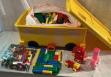 A yellow plastic school bus loaded with a bag of assorted colorful legos. - thumbnail 1 of 6