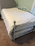 White metal trundle bed frame with upholstered headboard, white quilt, and floral-pattern mattress - thumbnail 2 of 5