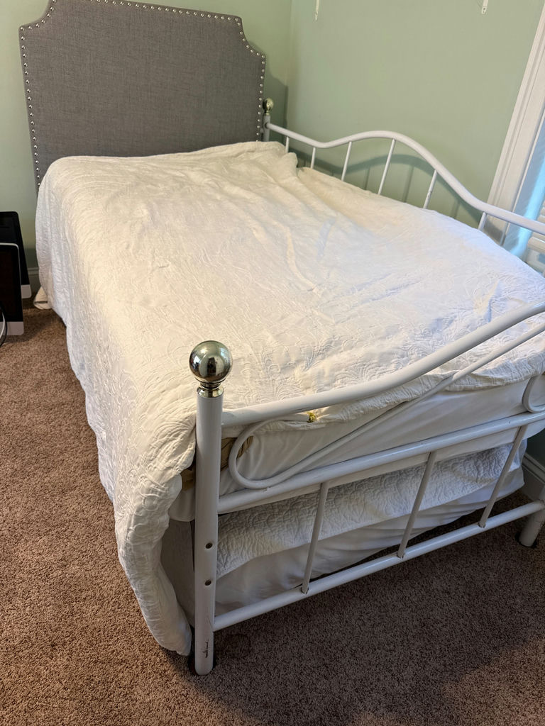 White metal trundle bed frame with upholstered headboard, white quilt, and floral-pattern mattress - image 1 of 5