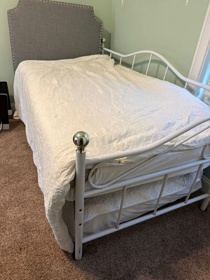 White metal trundle  bed frame with upholstered headboard, white quilt, and floral-pattern mattress - Image 1 of 5