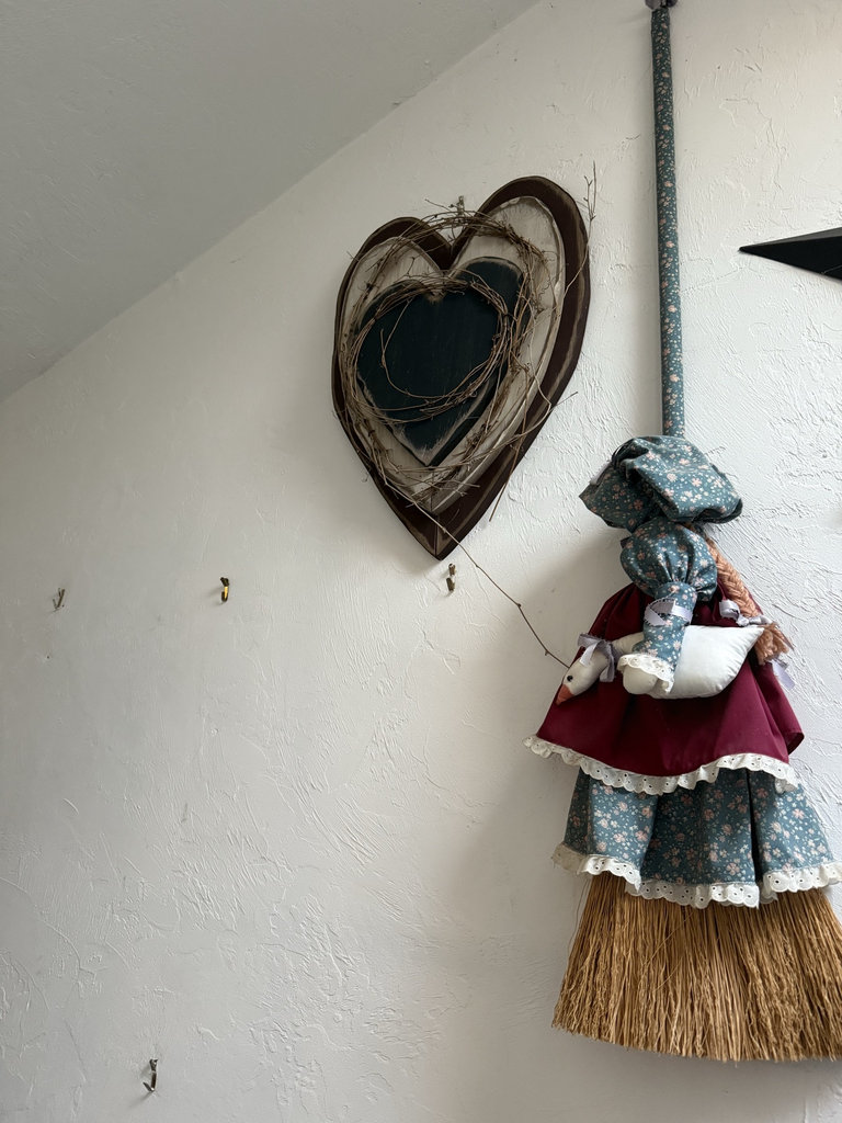 Heart-shaped wooden plaque with twine wreath and decorative fabric doll on a straw broom - image 1 of 5