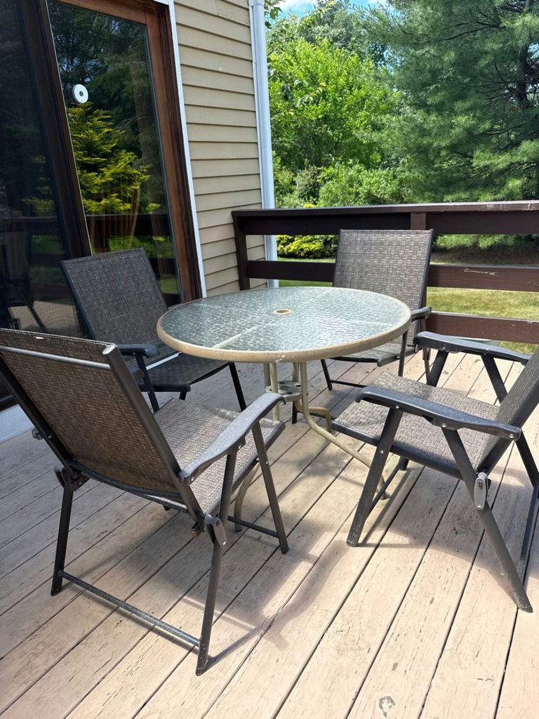Round glass-top patio table with four metal chairs - image 1 of 3