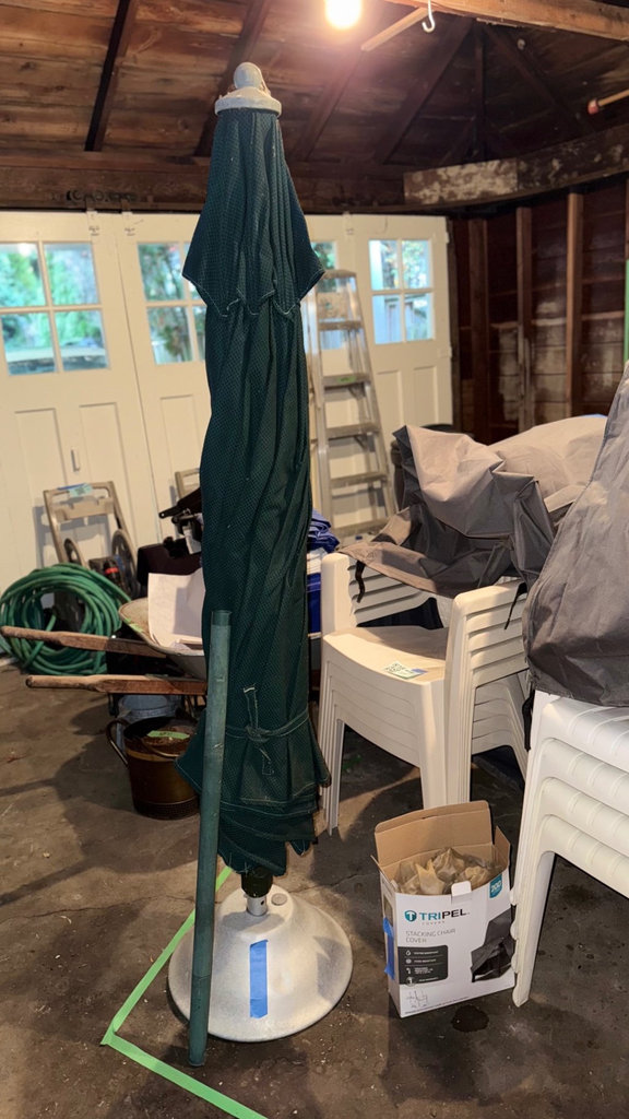Folded green patterned outdoor umbrella with base - image 1 of 5