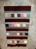 Geometric patterned woven rug with fringe and a white card with a square code - 50" x 29" - thumbnail 1 of 4