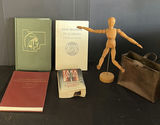Assorted vintage books, a wooden mannequin, and a metal tote - thumbnail 1 of 5