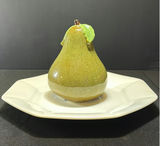 Ceramic pear-shaped figurine on white plate - thumbnail 1 of 5