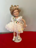 Shirley Temple Doll with White Pleated Dress and Floral Sash - thumbnail 1 of 2