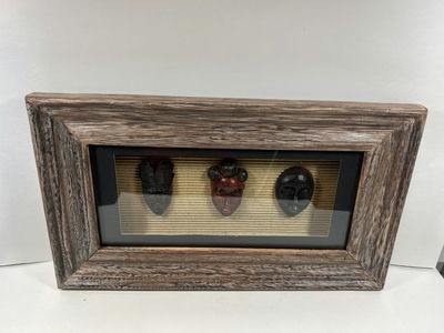 Three carved masks in a rustic framed display - Image 1 of 3