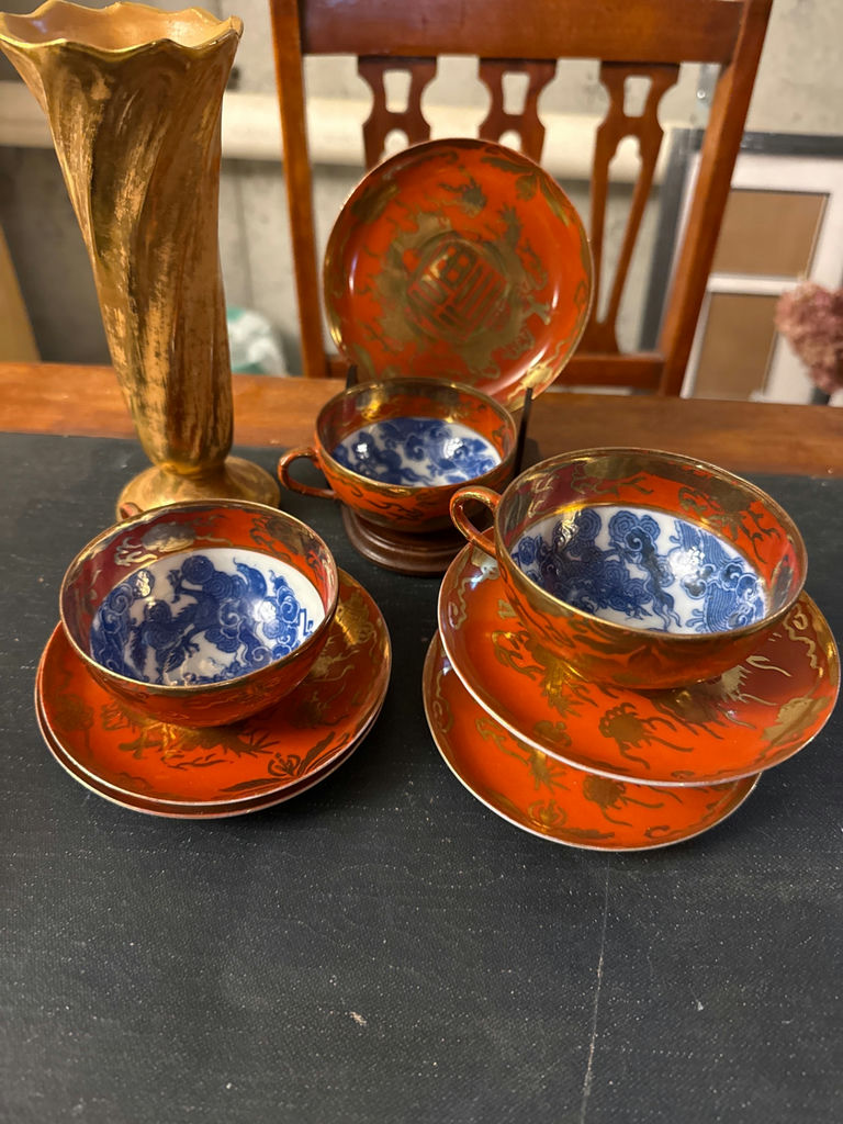 Orange-red porcelain teacups with blue interiors, matching saucers and plate, plus a gold vase - image 1 of 4
