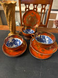 Orange-red porcelain teacups with blue interiors, matching saucers and plate, plus a gold vase - thumbnail 1 of 4