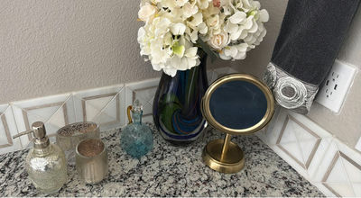 Hydrangea bouquet in blue glass vase with decorative bottles and brass mirror - Image 1 of 5