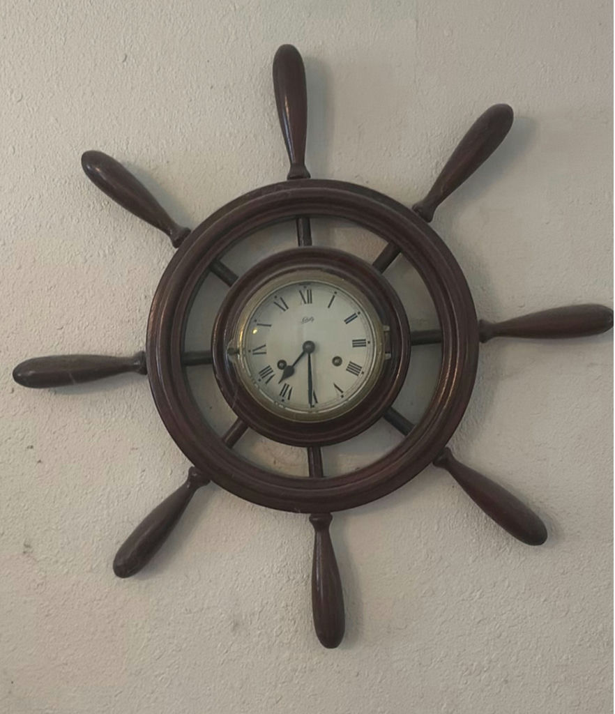 Vintage wall-mounted ship wheel clock, antique telephone, and wooden wall rack - image 5 of 8