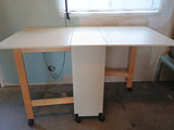 White foldable table with central pedestal and wooden legs on casters - thumbnail 1 of 6