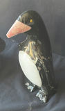Assorted decorative items including penguin figurines, an ornate tin, a jewelry box with knotted bracelets, a glass sculpture, and round coasters - thumbnail 7 of 8