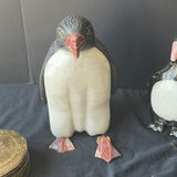 Assorted decorative items including penguin figurines, an ornate tin, a jewelry box with knotted bracelets, a glass sculpture, and round coasters - thumbnail 4 of 8