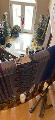 Patterned throw on stair railing with holiday trees and vacuum - Image 1 of 2