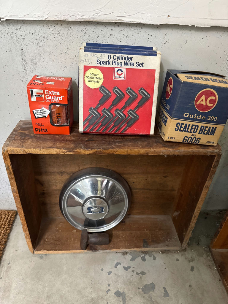 Oil filter box, spark plug wire set box, sealed beam headlight box, Chevrolet hubcap, and hammer - image 1 of 3