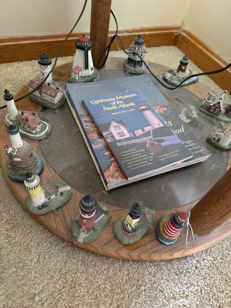 Lighthouse miniatures surrounding a book - image 2 of 3