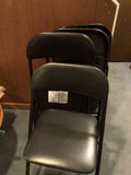 Stacked black folding chairs and card table - thumbnail 3 of 4