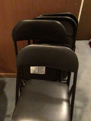 Stacked black folding chairs and card table - Image 1 of 4