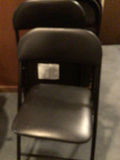 Stacked black folding chairs and card table - thumbnail 2 of 4