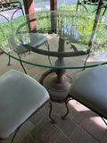 Round glass dining table with four cushioned metal chairs - thumbnail 3 of 4