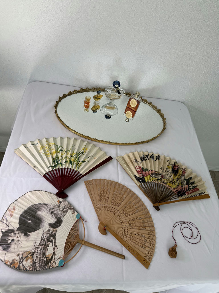 Oval gilt-mild mirror with vintage perfume bottles and decorative folding fans - image 1 of 5