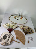 Oval gilt-mild mirror with vintage perfume bottles and decorative folding fans - thumbnail 1 of 5