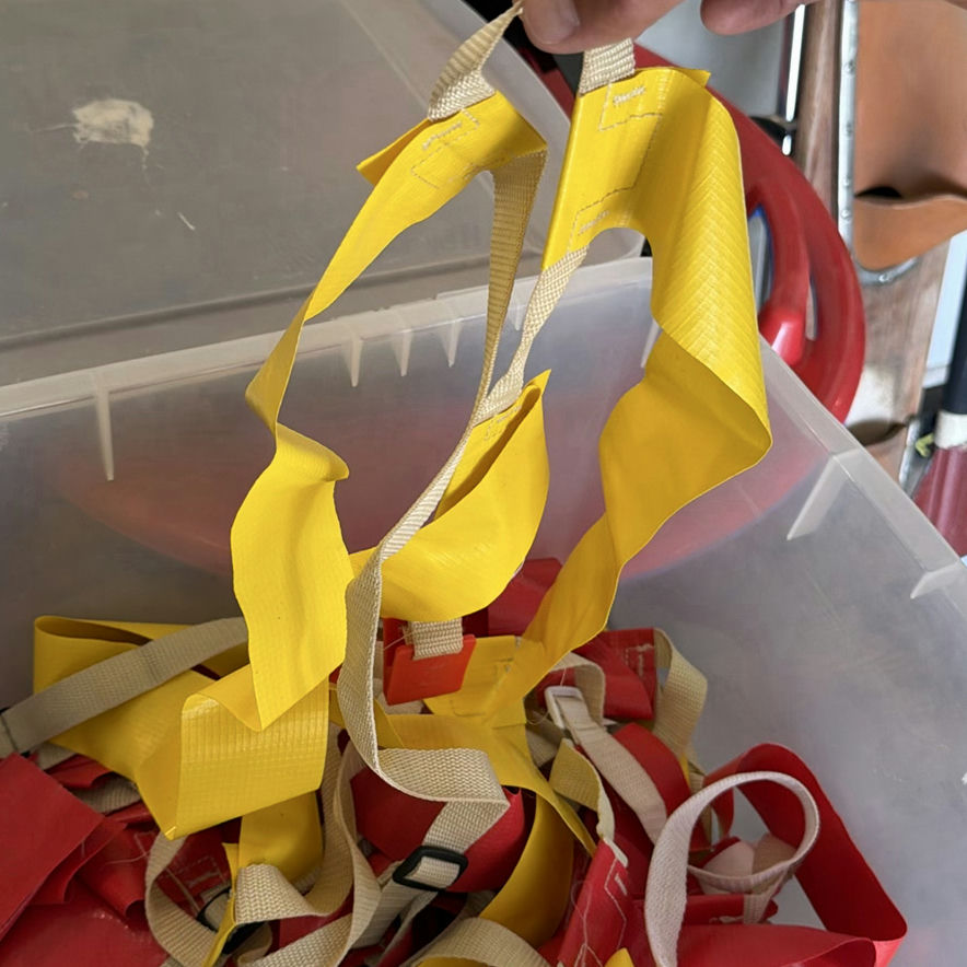 Assorted household items: box, curved plastic component with latch, bin of red and yellow straps, and towel - image 4 of 5