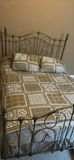 Ornate metal bed frame with quilted bedding - thumbnail 1 of 6