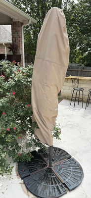 Beige folded patio umbrella with blue interior canopy on round base - Image 1 of 5