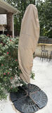 Beige folded patio umbrella with blue interior canopy on round base - thumbnail 1 of 5