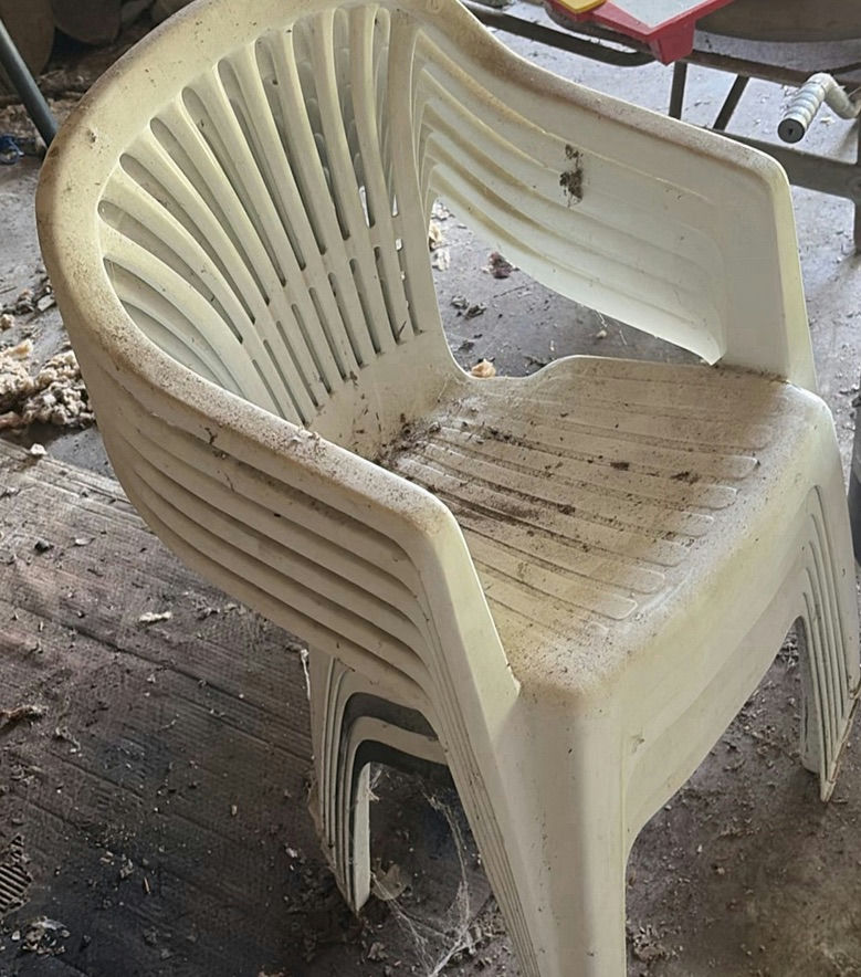 Stack of white plastic chairs and a black cylindrical metal trash can - image 1 of 4