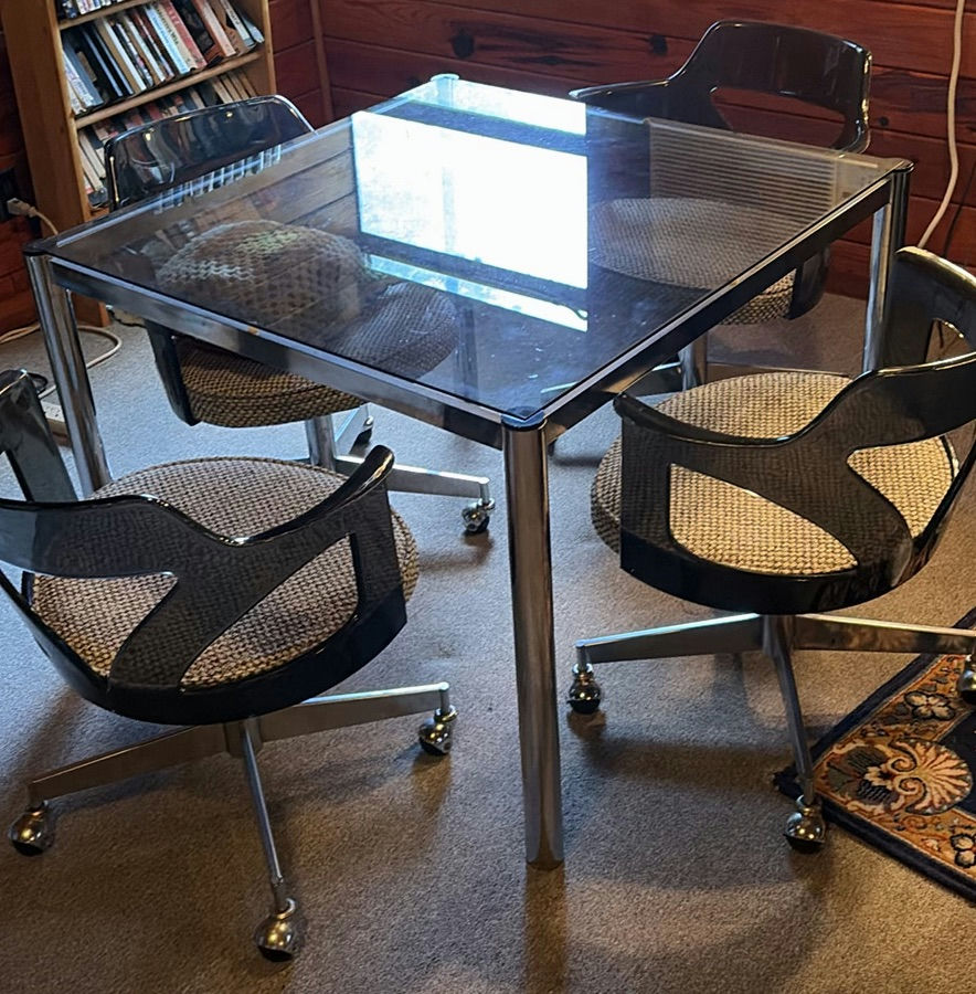 Glass-top dining table with four chrome-and-black swivel chairs - image 1 of 8